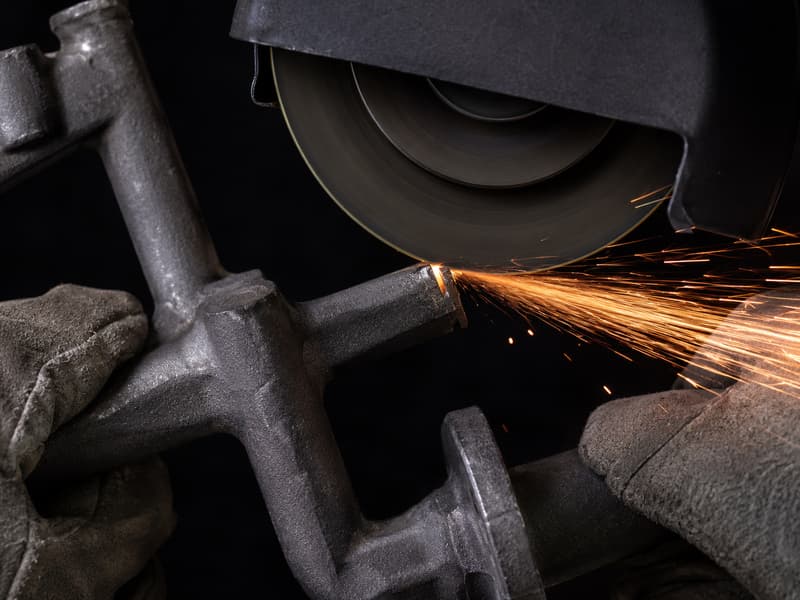 Sparks flying as a cut-off wheel removes a gate from a casting cluster